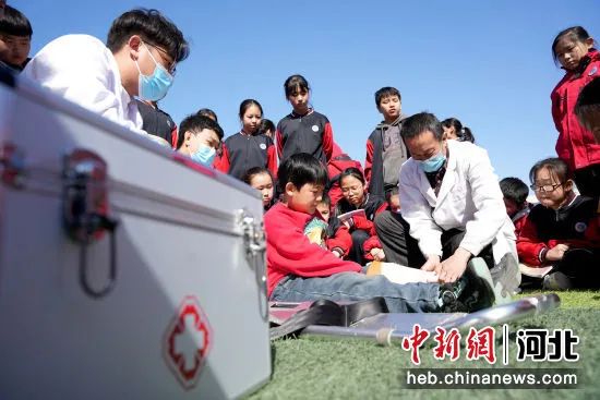 图为河北省隆尧县第五实验小学操场，救护人员现场演示对肢体受伤学生进行包扎救治。张玲玲 摄.jpg